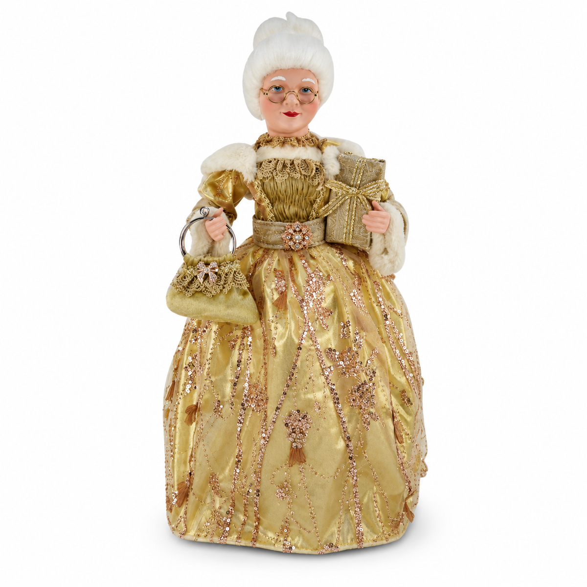 A vintage-style collectible doll dressed in an ornate gold gown with sequins, white fur trim, and a white powdered wig, holding a matching gold handbag and wrapped presents against a plain white background.