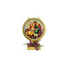 A circular Christmas nativity wall hanging with a gold-toned frame, featuring an illustration of Mary, Joseph, baby Jesus, and a sheep, mounted on a small decorative base with red ribbon and greenery.
