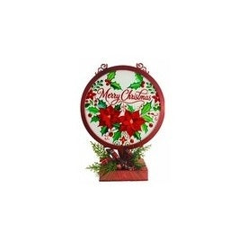 A round hanging Christmas sign with a red border, featuring red poinsettias, green holly leaves, pinecones, and the words 'Merry Christmas' in red script, mounted on a small red base with greenery at the bottom.